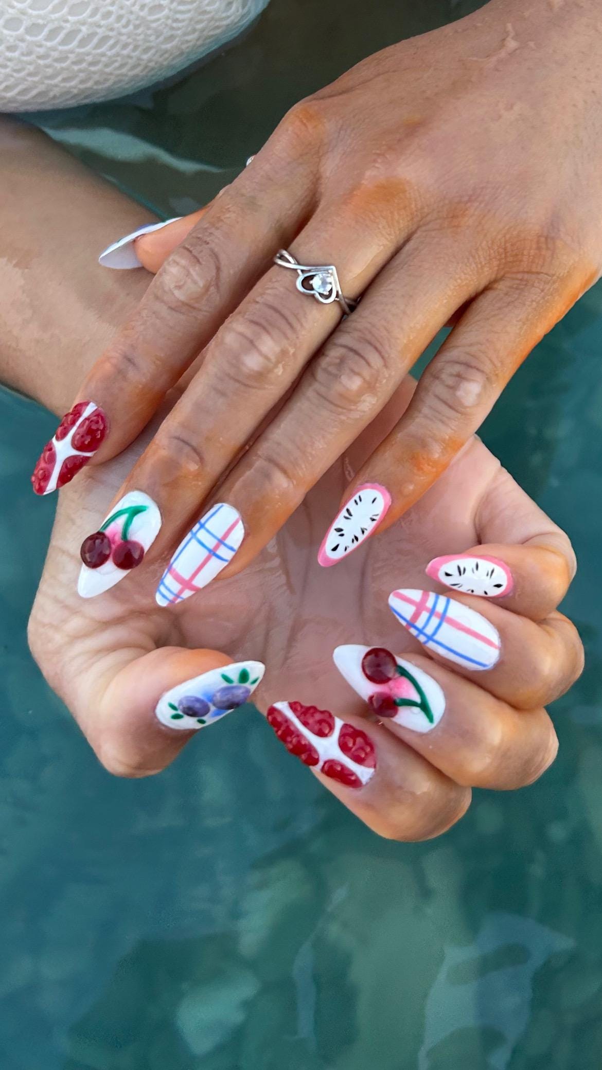 Handmade press-on nail in a spring style, featuring fruits and a picnic tablecloth/ Faux ongles "press-on" faits main au style printanier, avec des motifs de fruits et de nappe de pique-nique.