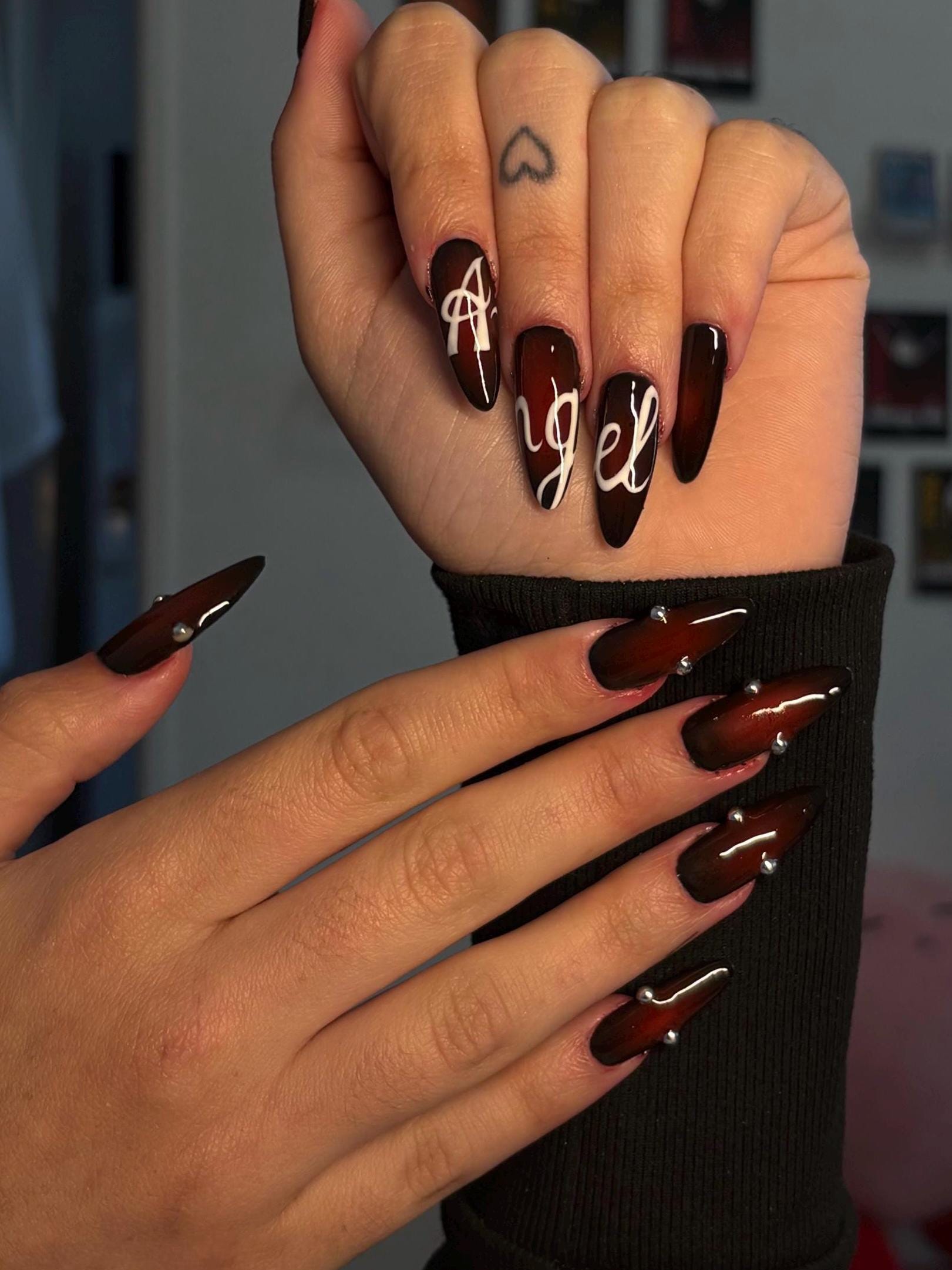Black press-on nail, red airbrush, white calligraphy, and silver pearls