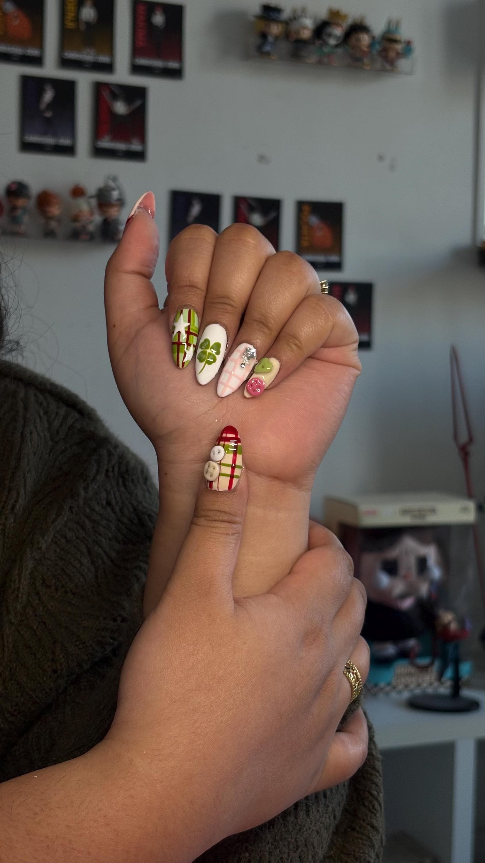 Press-on nail featuring apple, cat and button motifs in shades of red, green, and beige/ Faux ongles "press-on" avec motifs de pommes, chats et boutons, dans les tons rouge, vert et beige.